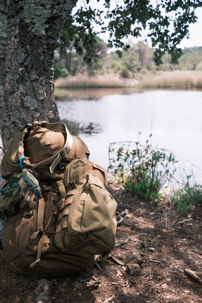 a backpack survival bag sitting on the ground next to a tree