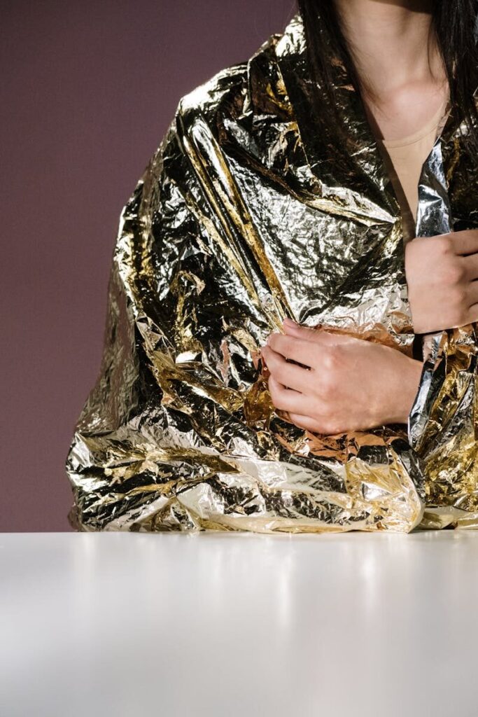 Utilisation d'une couverture de survie dorée/argentée entièrement dépliée tenue par deux mains