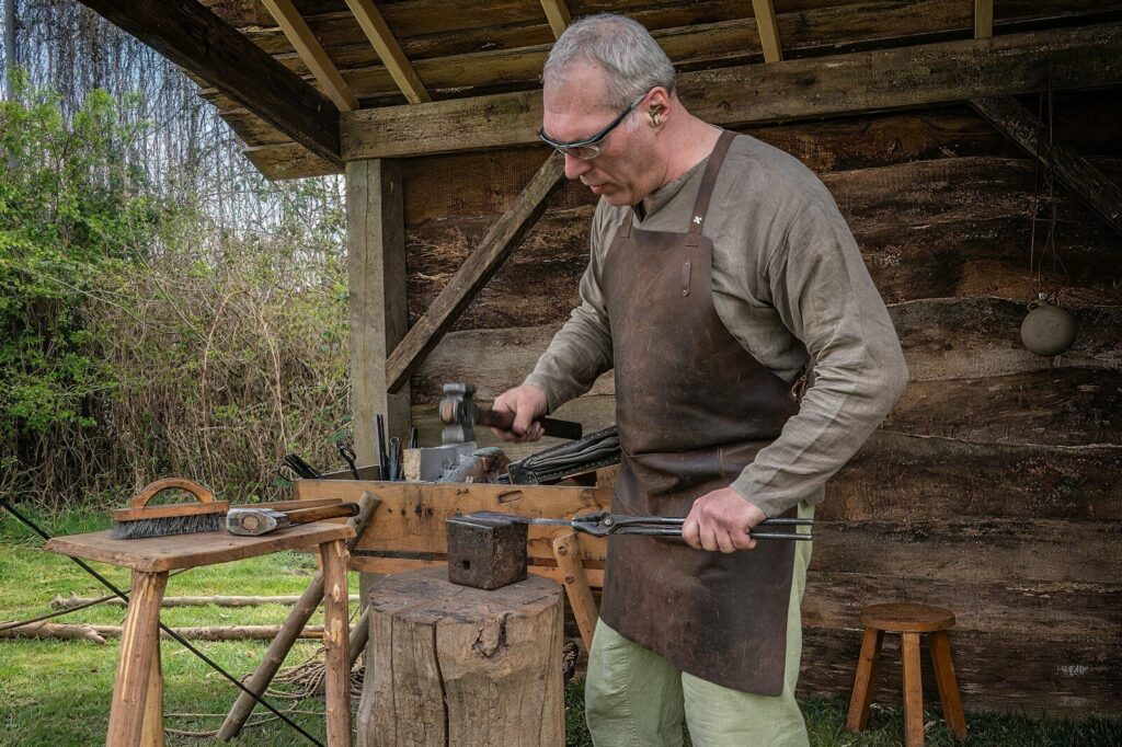 Artisan forgeron coutelier façonnant la soie d'une lame de couteau à l'enclume