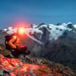 Lampe frontale LED allumée sur randonneur en forêt de nuit — éclairage survie trail