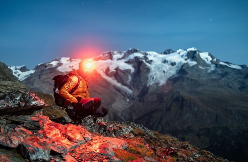 Lampe frontale LED allumée sur randonneur en forêt de nuit — éclairage survie trail