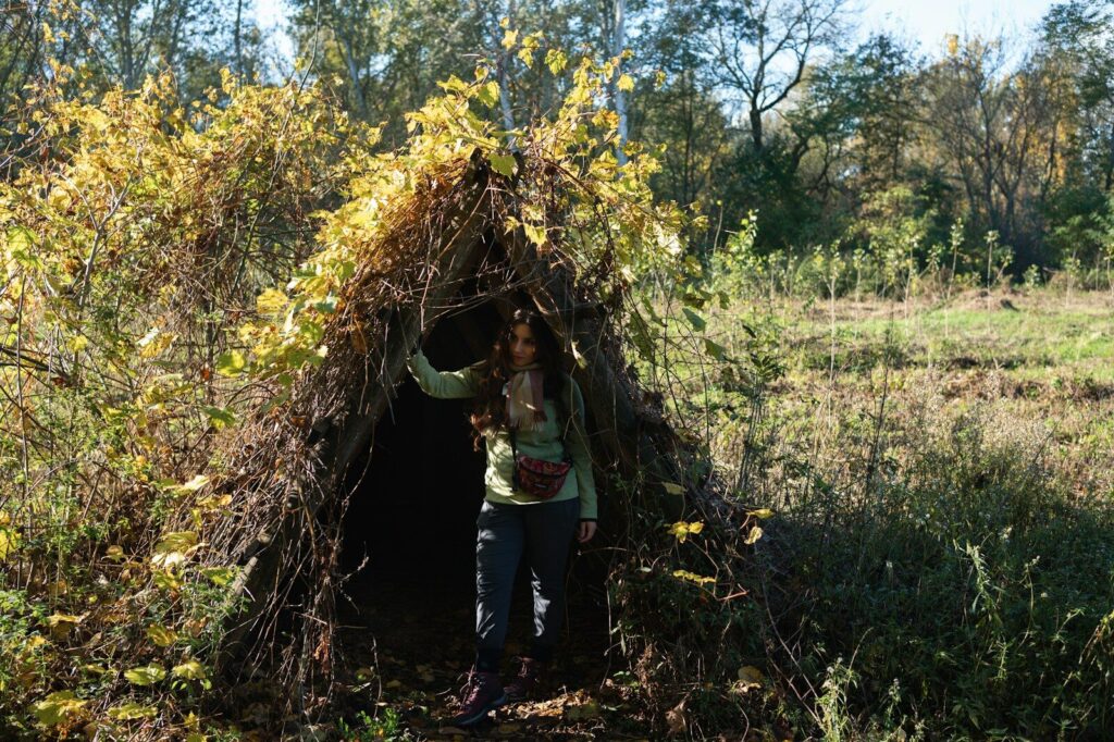Abri de survie en débris végétaux dans une forêt dense