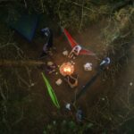 Comment faire un feu sans allumettes - Forêt sous la pluie avec petit feu allumé à l'abri de branches, braise protégée