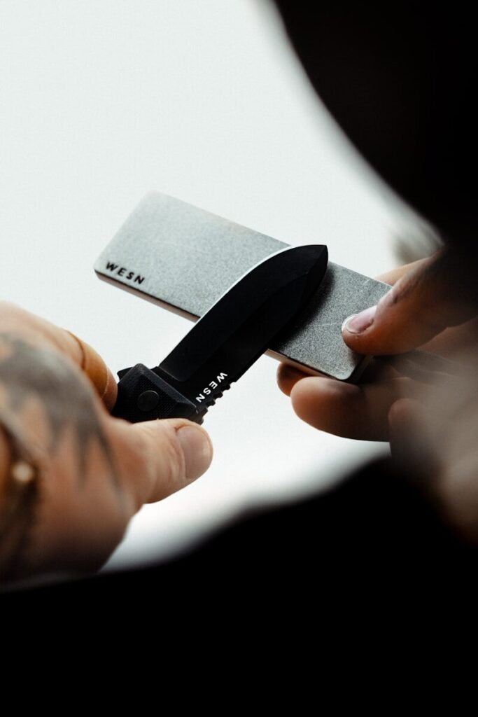 Affûtage d'un couteau de survie sur une pierre à affûter en extérieur