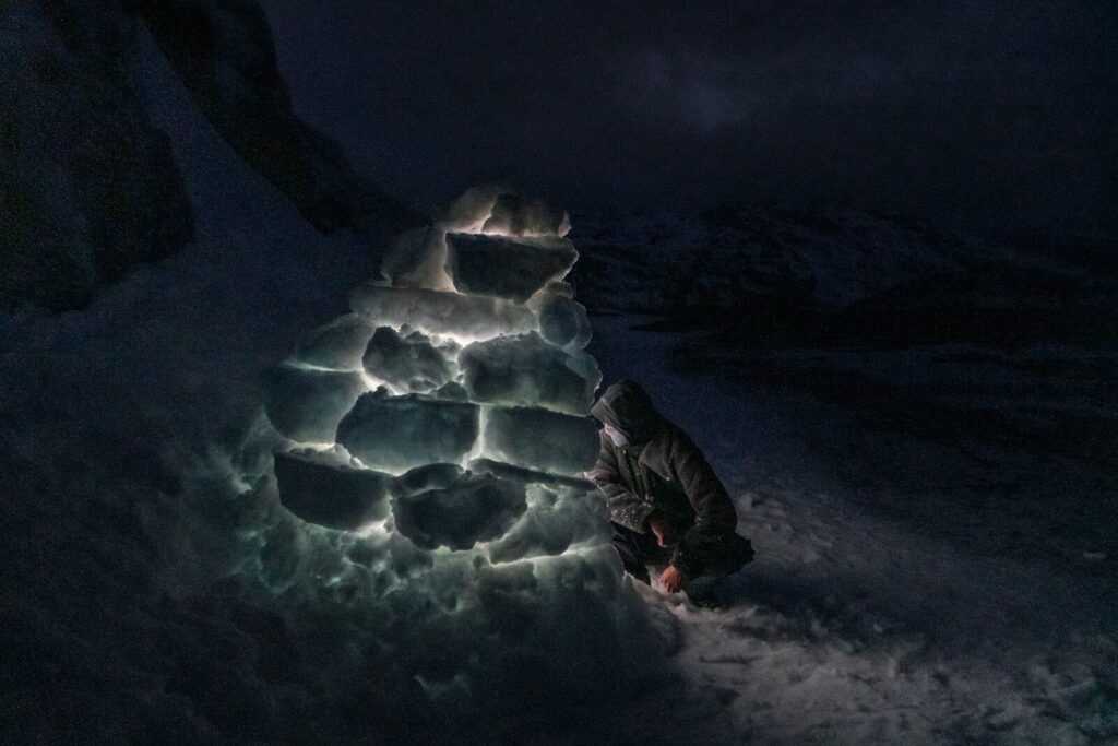 Abri de survie hivernal en forêt enneigée